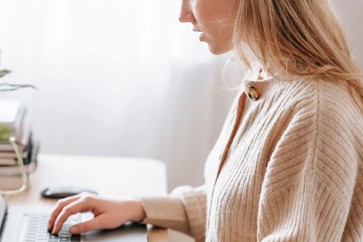 A freelancer working on a laptop at a bright home desk.